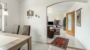A modern living room with a dining area, a television, and a fireplace. - Holiday Apartment 'Auszeit Sauerland' with Private Terrace and Garden (Meinerzhagen)