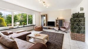 A living room with a sofa, a coffee table, a TV, and a fireplace. - Holiday Apartment 'Auszeit Sauerland' with Private Terrace and Garden (Meinerzhagen)