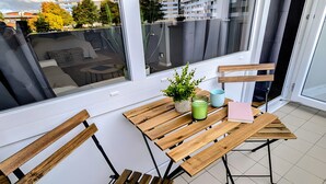 Ein Balkon mit Holzmöbeln, einem Blumentopf und einem Buch.