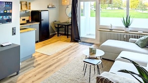 Eine moderne Küche mit Essbereich, einer Couch und Blick auf eine grüne Landschaft.