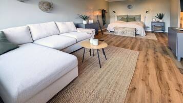A modern living room with a sofa, a coffee table, a bed, and a small side table.