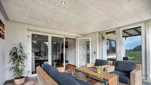 Een moderne woonkamer met rieten meubels, een glazen bijzettafeltje en een potplant.