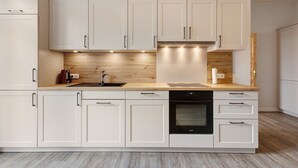 A modern kitchen with white cabinetry, a wooden countertop, and built-in appliances. - Apartment 'Reit- Und Ferienhof Alte Dorfschule' with  Private Terrace and Wi-Fi (Holstenniendorf)