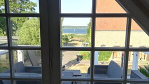Een kamer met een groot raam dat uitkijkt op een terras met tuinmeubilair.