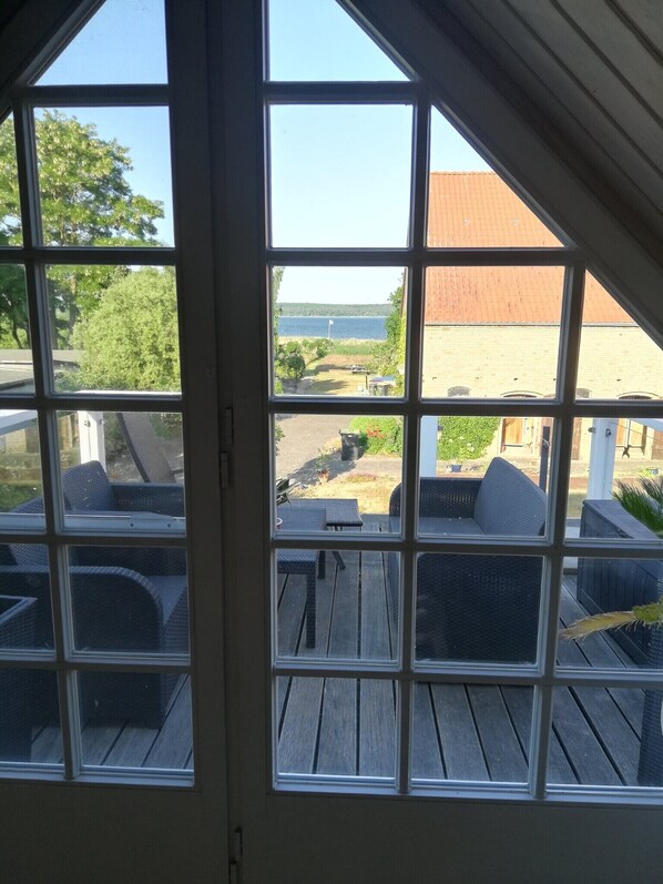 A room with a large window overlooking a deck with outdoor furniture.