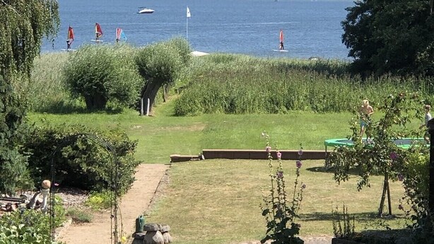 Een tuin met uitzicht op een meer, een pad en een kleine vijver.