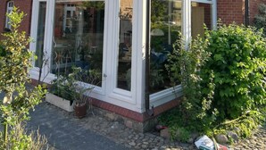 Een huis met een conservatorium, bakstenen muren en een pannendak.