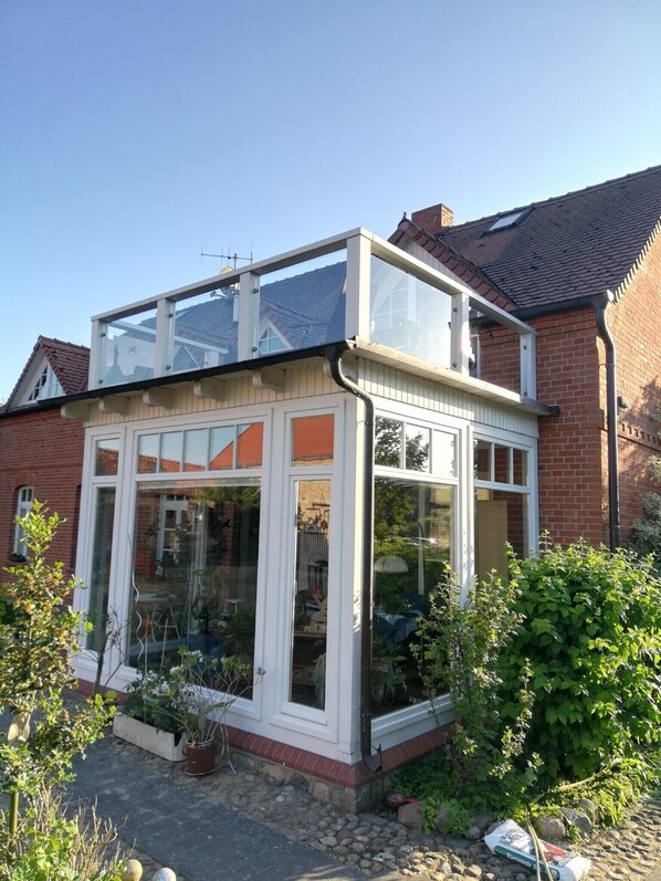 A house with a conservatory, brick walls, and a tiled roof.