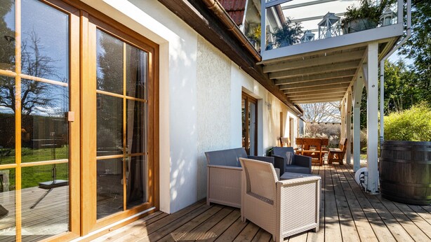 Een houten terras met rieten meubilair en een pergola.