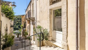A narrow street with buildings, a staircase, and a door.