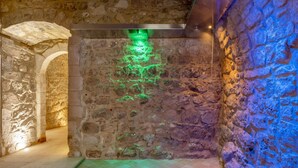 Interior con paredes de piedra, una lámpara verde y suelo de cuadros.