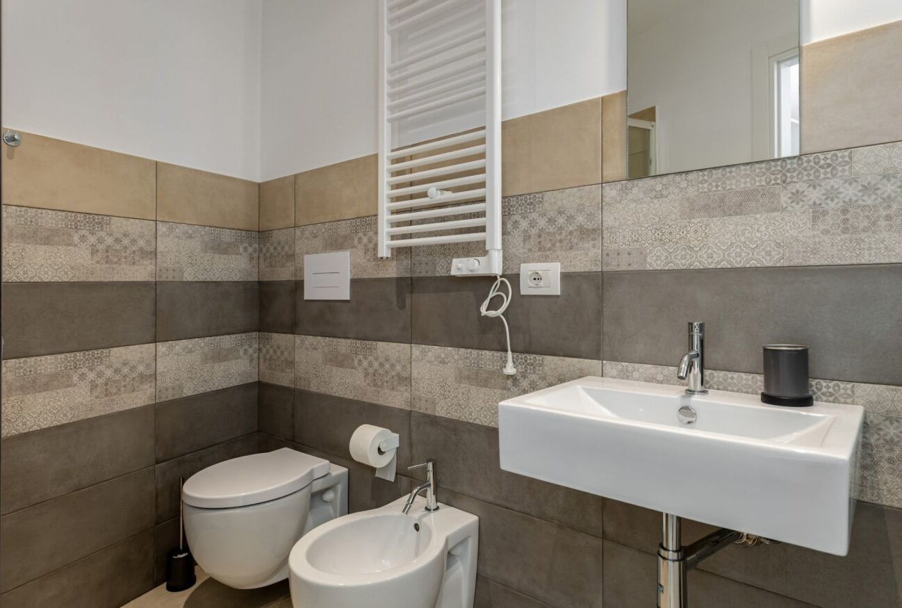 Un baño con inodoro, bidé y lavamanos con espejo.