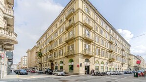 A multi-story building with balconies, a street in front, and parked cars. - GuestHost - Lovely Retreat for 2 - 400 m far from Porta Nuova (Torino)