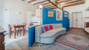 A modern interior with exposed wooden beams, a dining area, a sofa, and a kitchen. - GuestHost - Lovely Retreat for 2 - 400 m far from Porta Nuova (Torino)