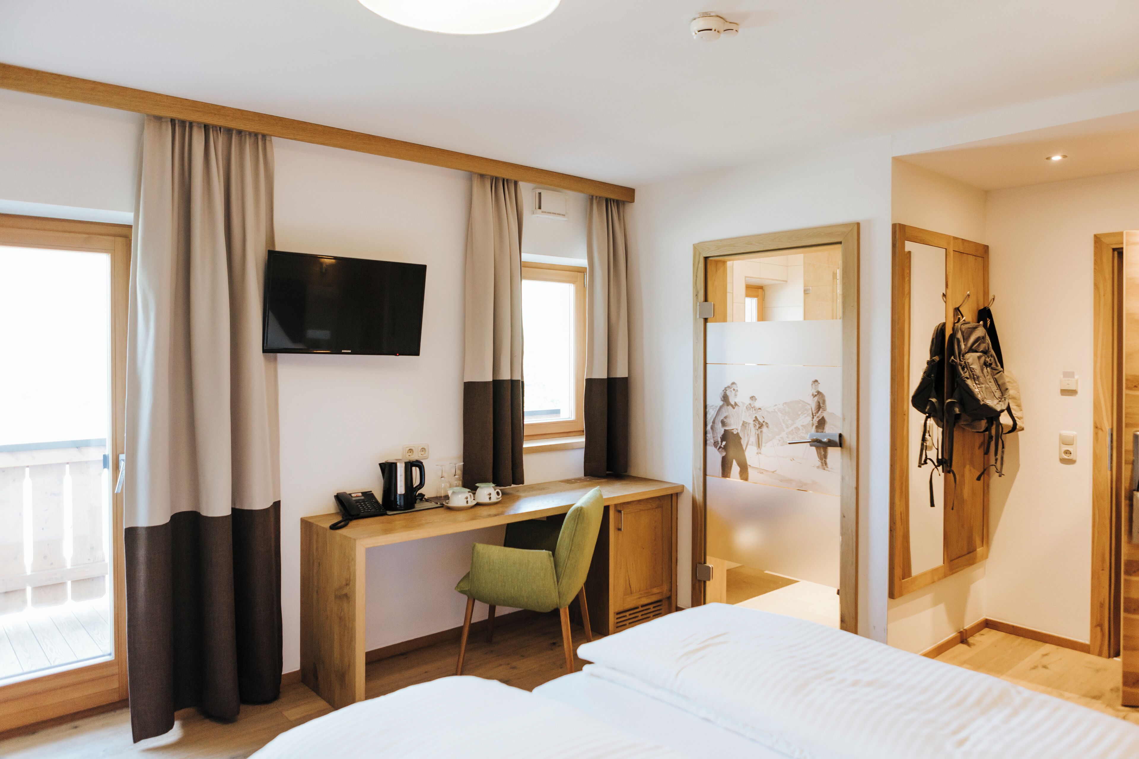 A hotel room with a bed, a desk with a chair, a television, and a wardrobe.