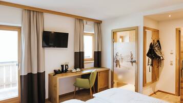 A hotel room with a bed, a desk with a chair, a television, and a wardrobe.