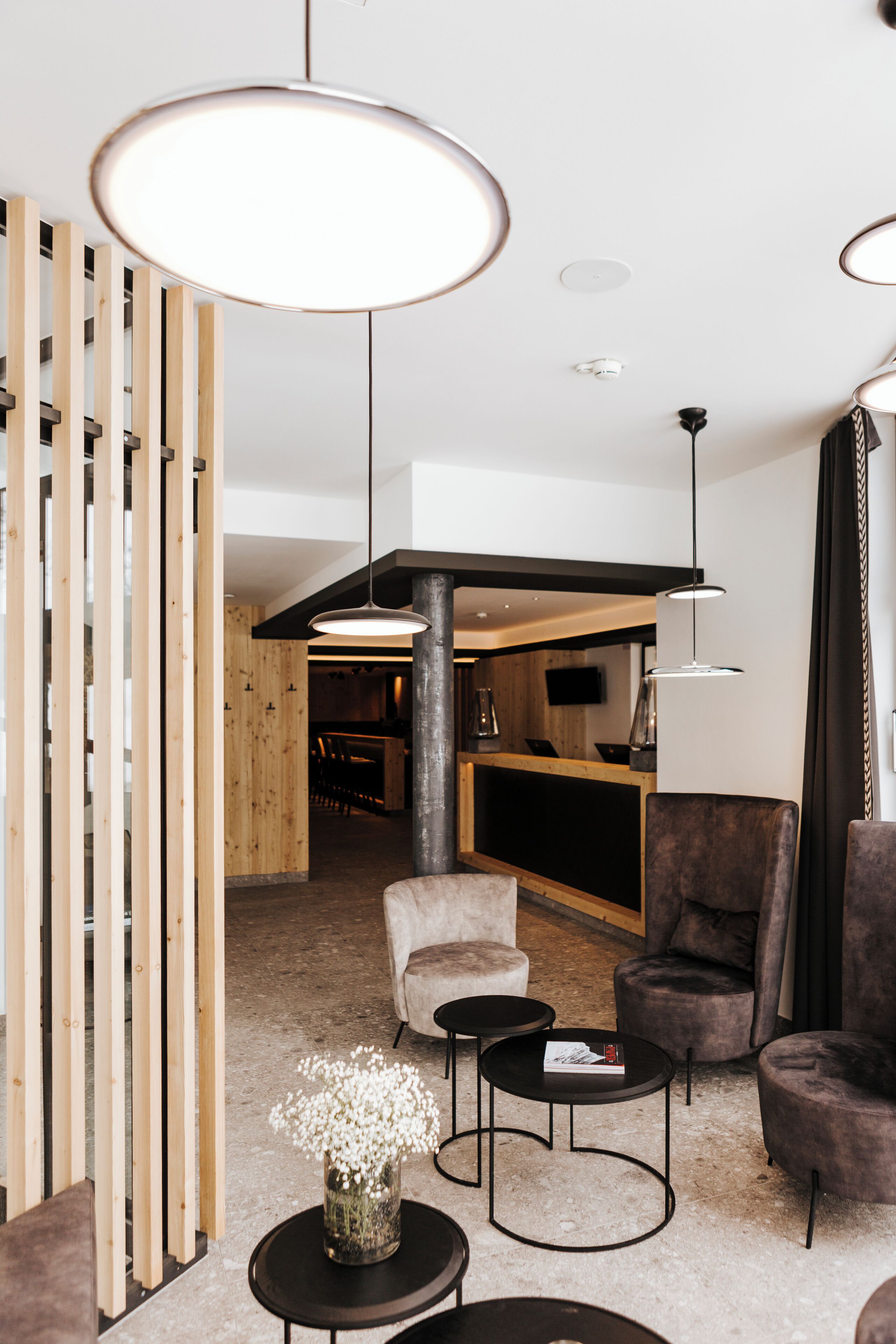 Un interior moderno con un separador de madera, un sofá, dos sillones y una mesa de centro.
