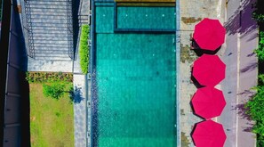 An aerial view of a swimming pool with a staircase leading to a covered area, surrounded by greenery and red umbrellas. - Ballena Regency (Mirissa)