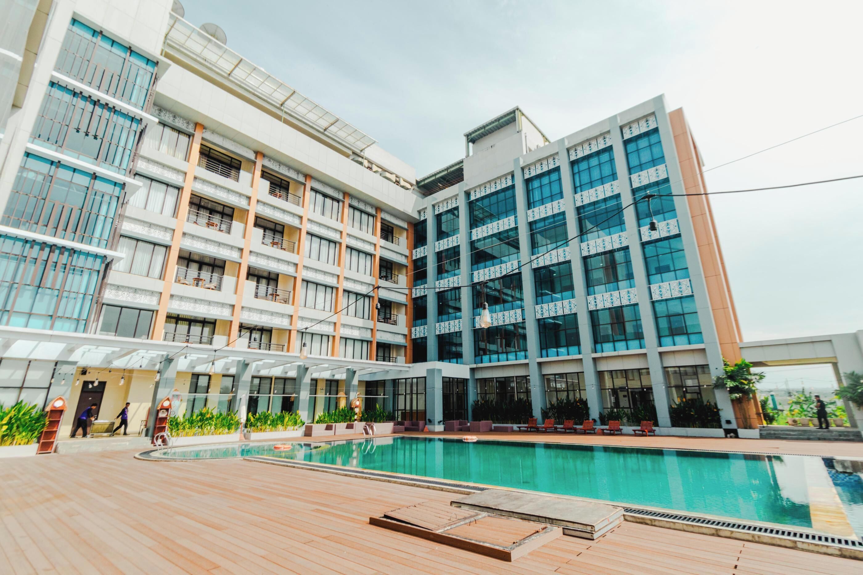 Un hotel moderno con una amplia piscina al aire libre, varios pisos y un paseo techado.