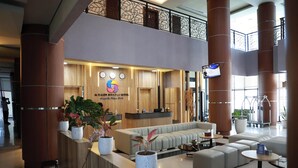 A hotel reception area with a modern design, featuring a reception desk, seating area, and large pillars. - De Balen Soultan Hotel (Jonggat)