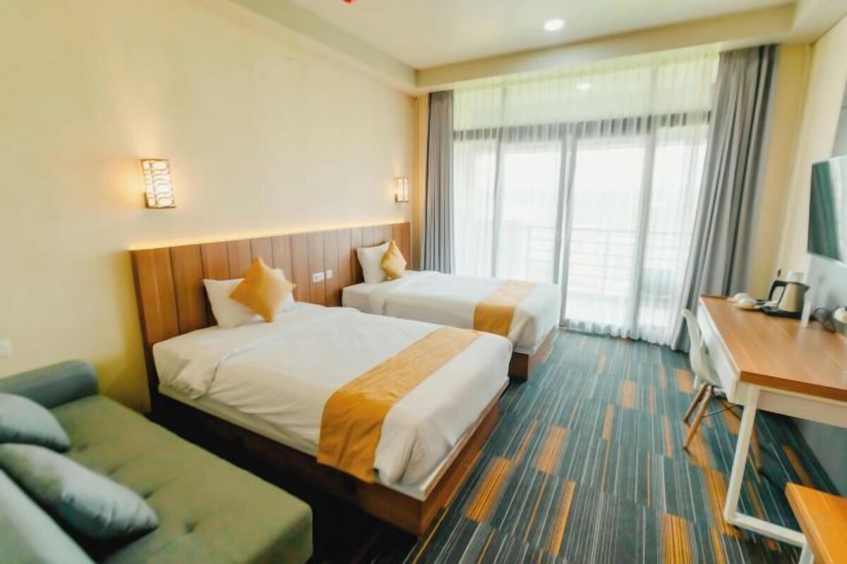 A hotel room with two beds, a desk, a chair, and a television.