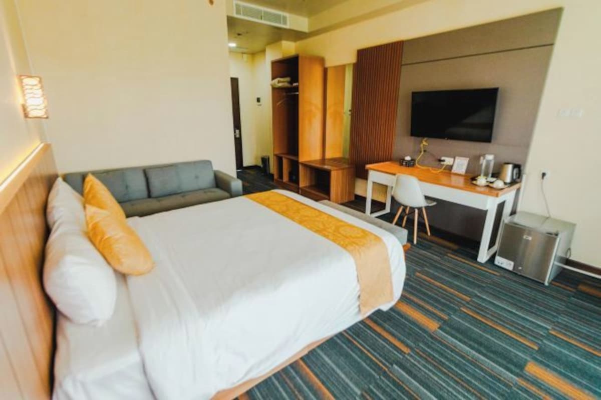 Una habitación de hotel con cama, escritorio y televisor.