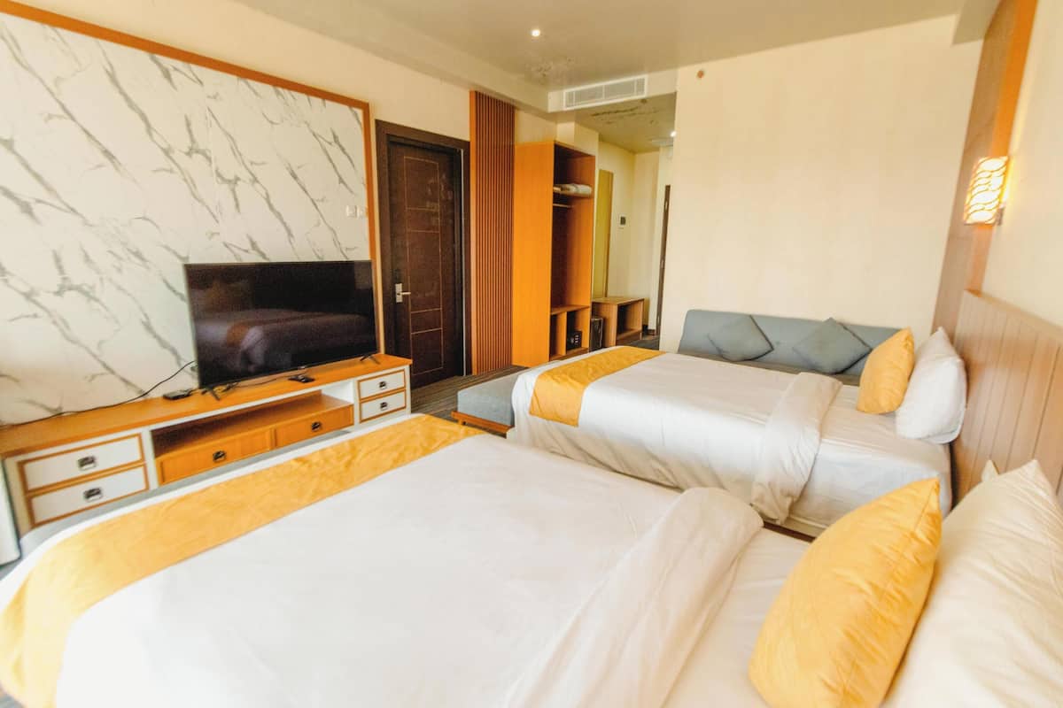 A hotel room with two beds, a television, a wooden dresser, and a mirror.