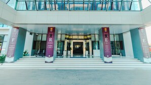 A modern building entrance with a glass facade, two large pillars, and a staircase leading up to the entrance. - De Balen Soultan Hotel (Jonggat)