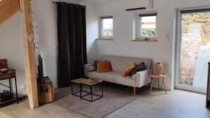 Una sala de estar acogedora con un sofá, una mesa de centro, una mesita auxiliar y una ventana con vistas al exterior.