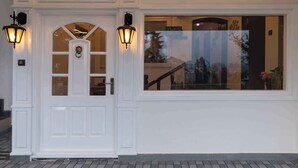 A white door with two wall-mounted lanterns, a window with a view of a staircase, and a decorative door knocker. - HERITAGE VIEW (Ootacamund)