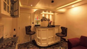 A bar area with two stools, a counter, and a shelf with bottles and a motorcycle decoration. - HERITAGE VIEW (Ootacamund)