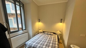 A compact bedroom with a metal bed frame, a small bedside table, and a chair. - Design micro apartment in the Porta Venezia Design District (Milano)
