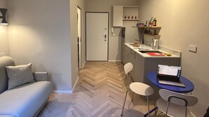 A compact living space with a sofa, a dining area with a laptop, and a kitchenette. - Design micro apartment in the Porta Venezia Design District (Milano)