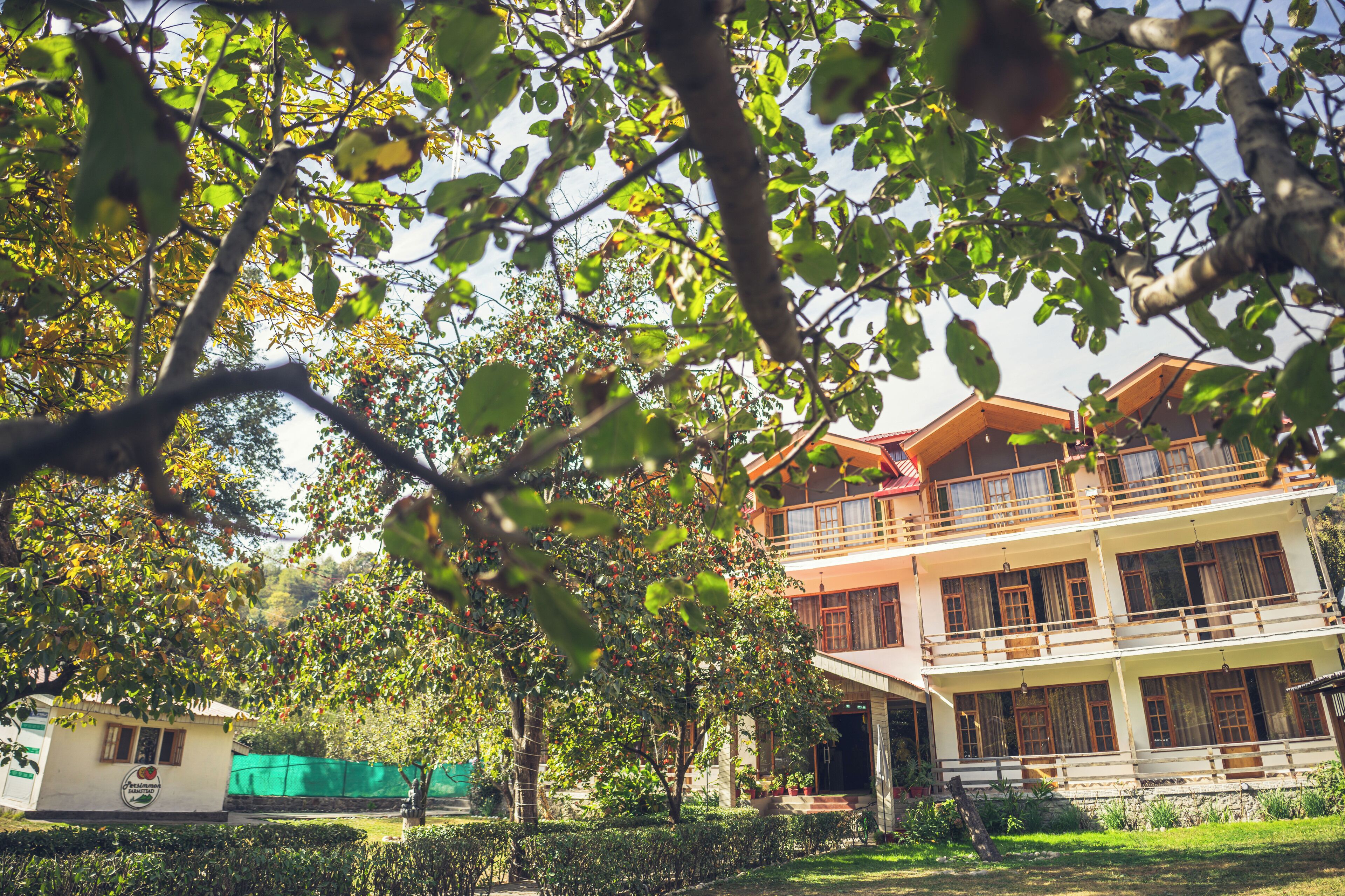 A two-story building with a balcony, surrounded by greenery and trees.