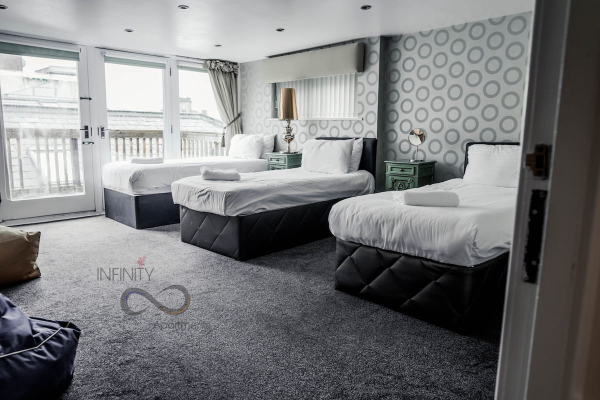 A hotel room with two beds, a large window, and a balcony.