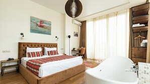 Une chambre à coucher avec un grand lit, une baignoire blanche et un plancher en bois.