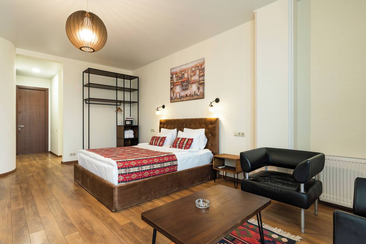 Une chambre à coucher avec un lit, une étagère suspendue, une chaise et une table.