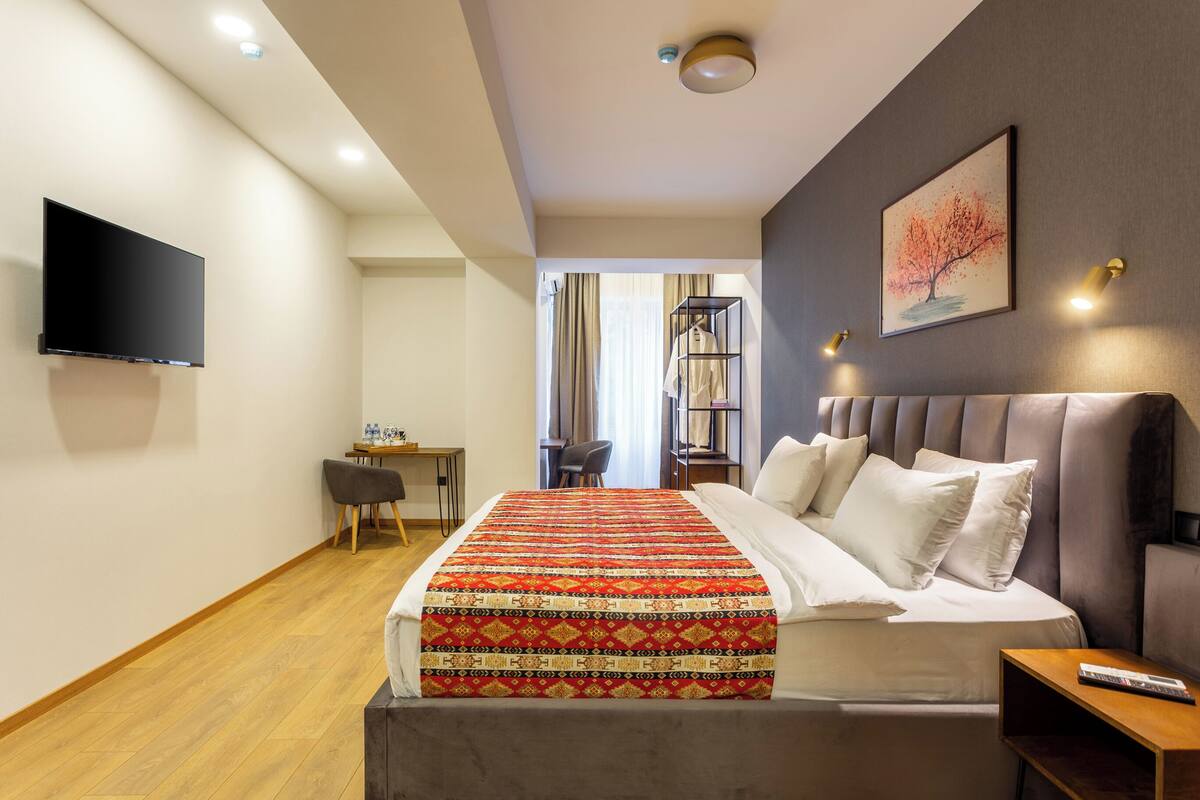 Une chambre d’hôtel moderne équipée d’un grand lit, d’un téléviseur à écran plat, d’un bureau et d’une chaise.