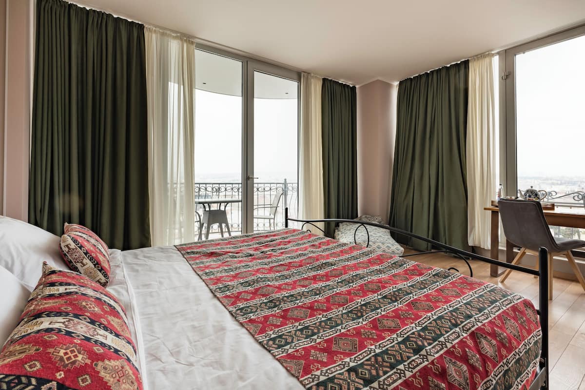 Une chambre d’hôtel avec un grand lit, un bureau et un balcon offrant une vue.