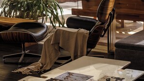 A modern lounge area with leather chairs, a coffee table with magazines, and a large window offering a view of greenery outside. - The K'rin Villa (Xuan Huong - Da Lat)