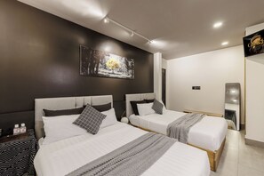 Hotellihuone, jossa on kaksi sänkyä, seinällä taulu, peili ja televisio.