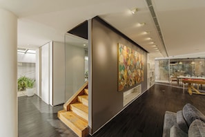 Ein modernes Interieur mit einer Treppe, einer Essecke und einem großen, abstrakten Gemälde.