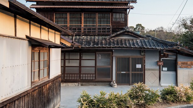 Ein traditionelles japanisches Gebäude mit einem Ziegeldach, Holzkonstruktion und großen Schiebetüren.