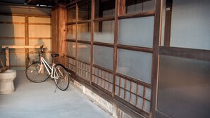 Ein traditioneller japanischer Raum mit Tatami-Böden, einer Holztür als Schiebetür und einem Fahrrad, das an der Wand lehnt.