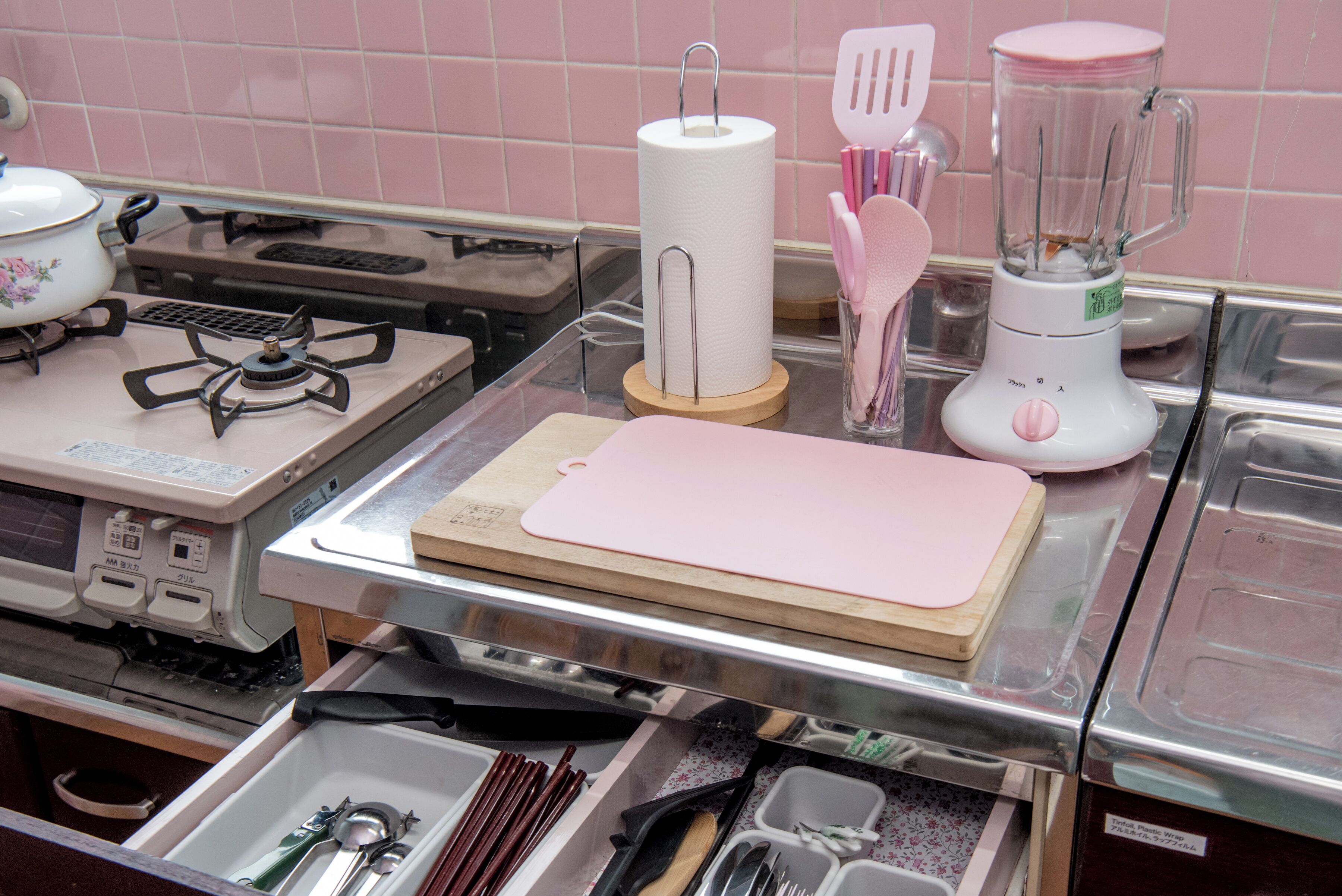 A kitchen with a gas stove, a blender, a cutting board, and various utensils.