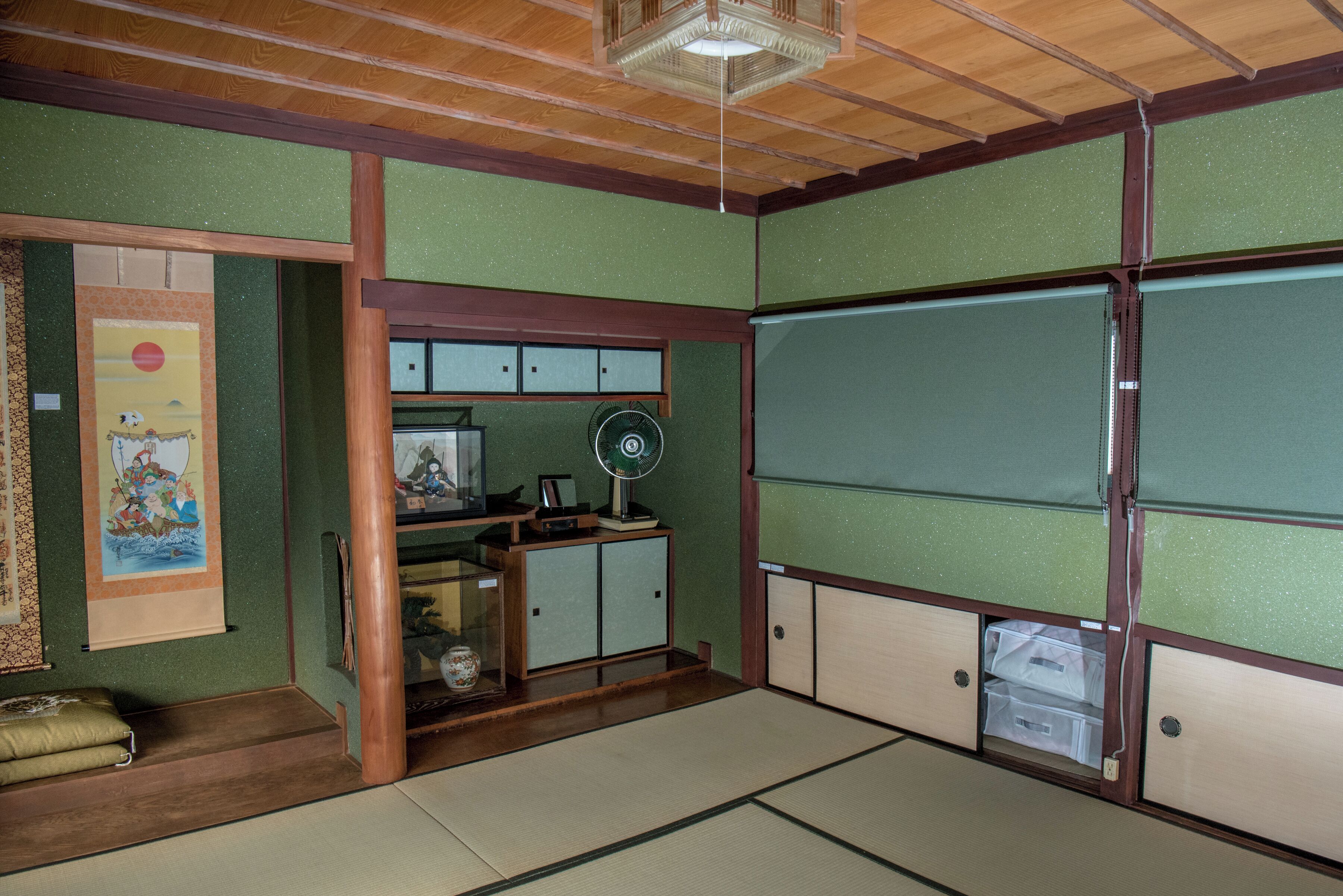 Una habitación japonesa tradicional con suelo de tatami, puertas correderas y un abanico.