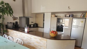 A modern kitchen with a central island, white cabinetry, and stainless steel appliances. - 3* family duplex near the sea, Spain and the mountains. Pets allowed (Le Boulou)