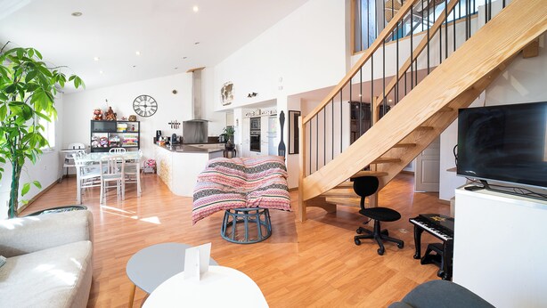A spacious living area with a wooden staircase, a dining area, and a kitchen in the background. - 3* family duplex near the sea, Spain and the mountains. Pets allowed (Le Boulou)