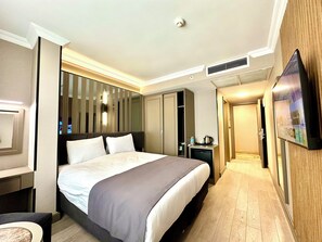 A hotel room with a bed, bedside table, TV, wardrobe, and a small kitchenette. - Aven Hotel (Istanbul)