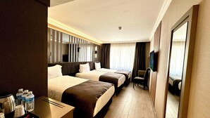 A hotel room with two beds, a desk with a tray of toiletries, a chair, and a television. - Aven Hotel (Istanbul)